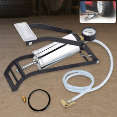 A black and silver foot pump with a hose and gauge is on a brown surface, with a small O-ring and valve stem nearby.