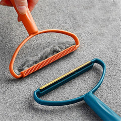 A hand holding an orange fabric brush lint remover covered in grey lint, next to a blue metal shaver lint remover.