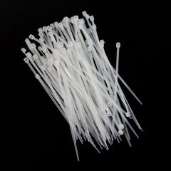 A large pile of white nylon cable ties scattered on a black background.