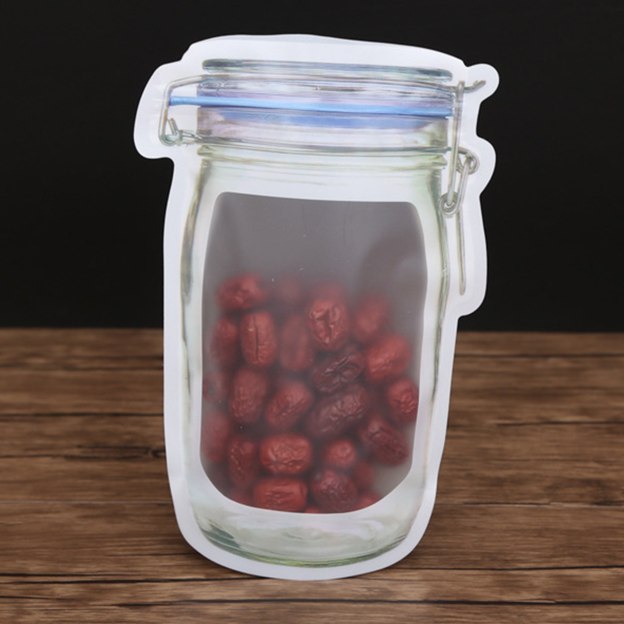 A clear, mason jar-shaped plastic bag filled with red dried dates sits on a dark wooden surface.