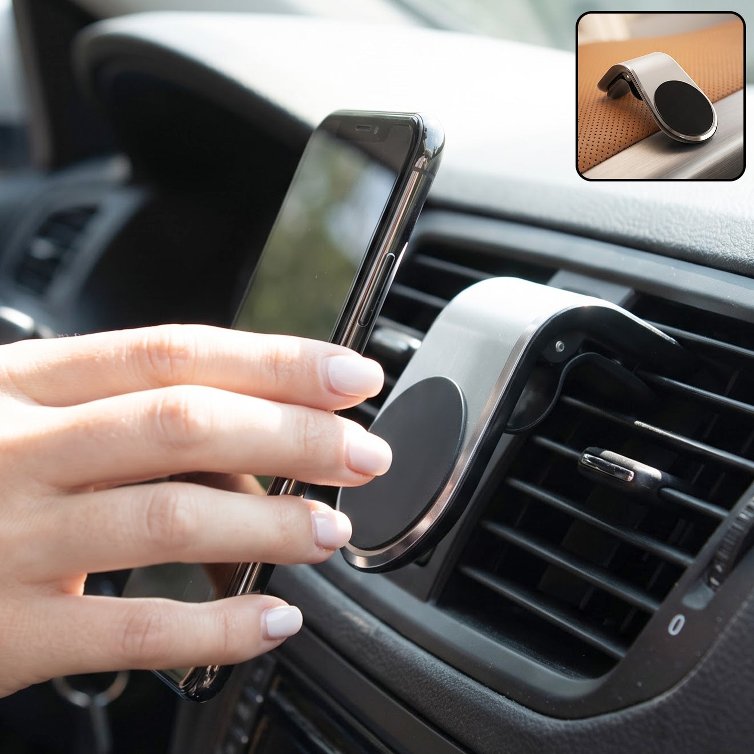 A hand places a smartphone onto a silver and black magnetic car phone holder attached to an air vent.