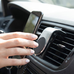 A silver and black magnetic car phone holder is shown on a light grey car interior surface.