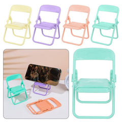 Four miniature foldable chairs in pastel yellow, purple, peach, and teal, with a phone resting on a purple stand.