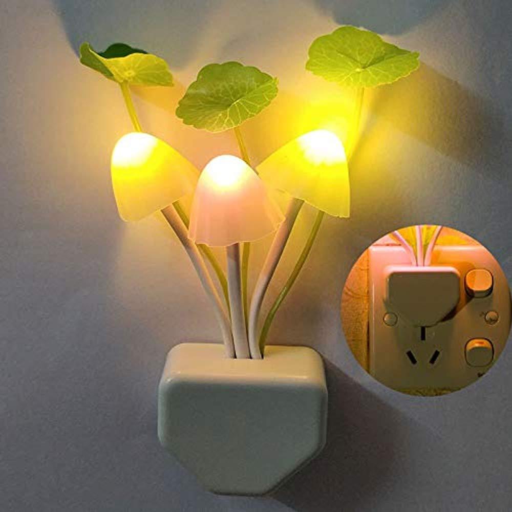 A mushroom night light with glowing yellow caps and green leaves is plugged into a wall, with an inset showing the plug