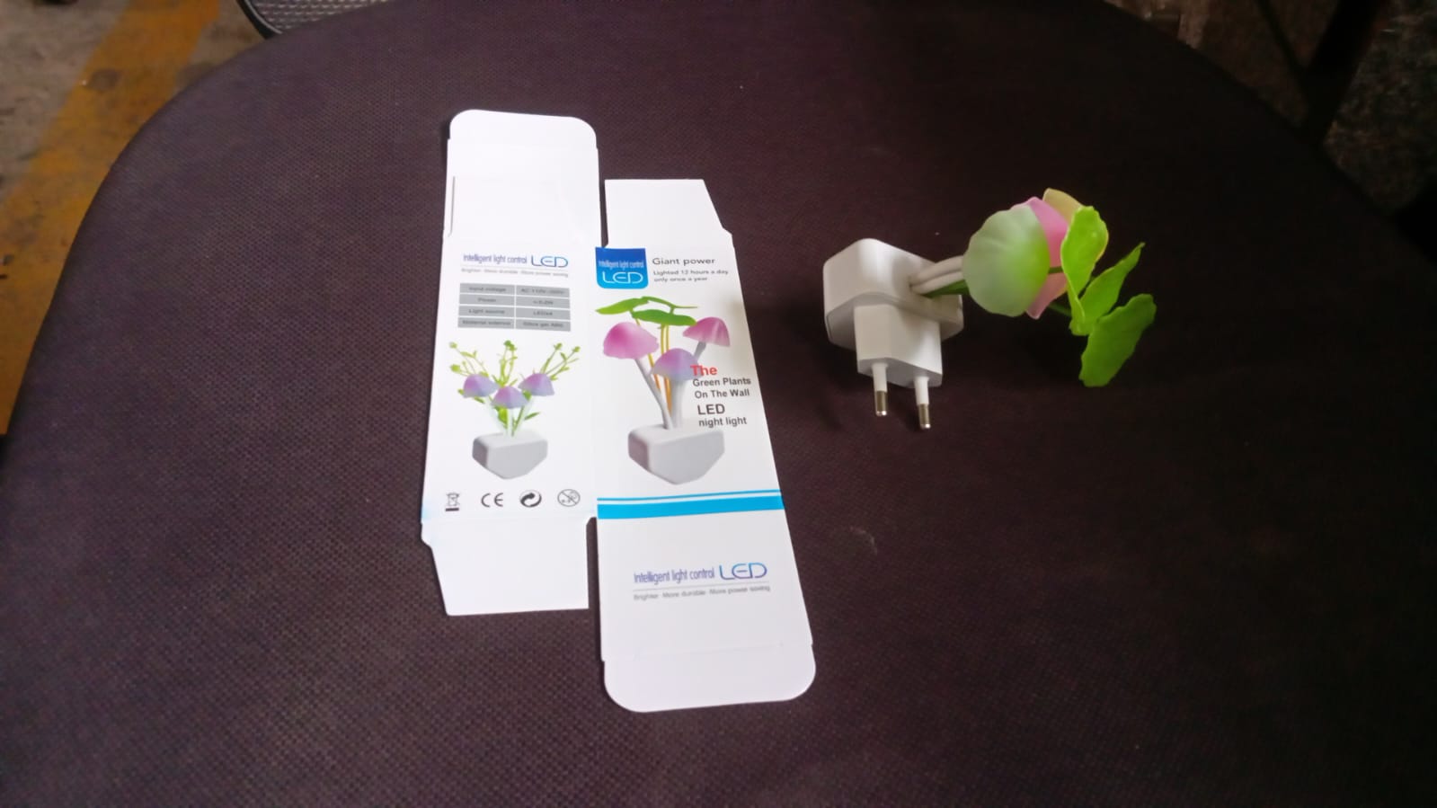 A mushroom night light and its packaging box are placed on a dark surface, with the box showing product illustrations.