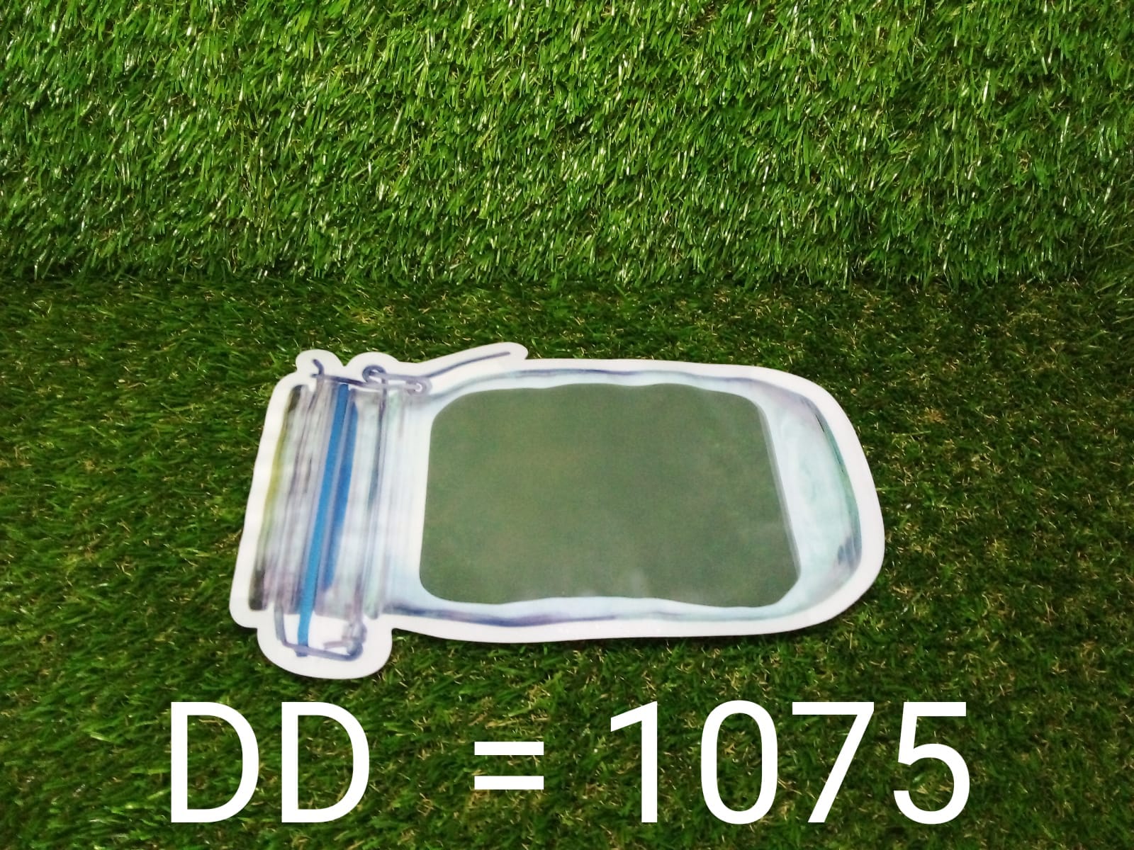 A clear, mason jar-shaped plastic bag lies horizontally on green artificial grass with