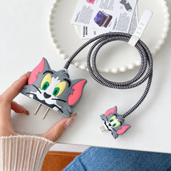 Hand holding a gray Tom cat silicone charger cover with a striped cable protector attached to a small connector.