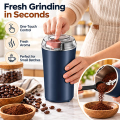 A person's hand pressing the button on a dark blue electric grinder, with coffee beans and ground coffee nearby.