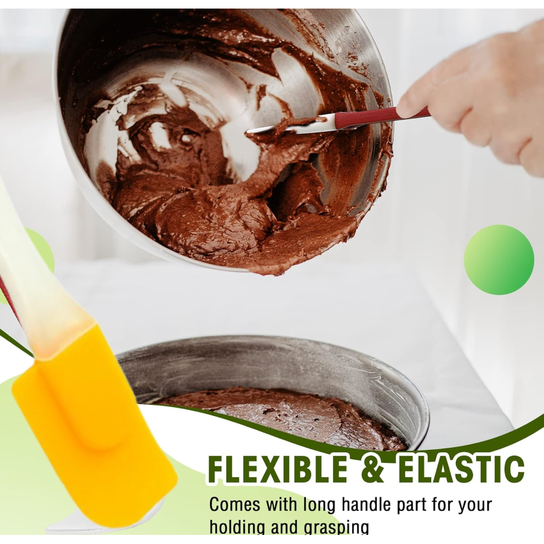 A yellow silicone spatula with a cream handle is partially visible, with a bowl of chocolate batter and a cake pan in the