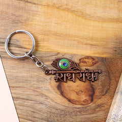 Close-up of Radhe Radhe copper keychain with detailed colorful peacock feather