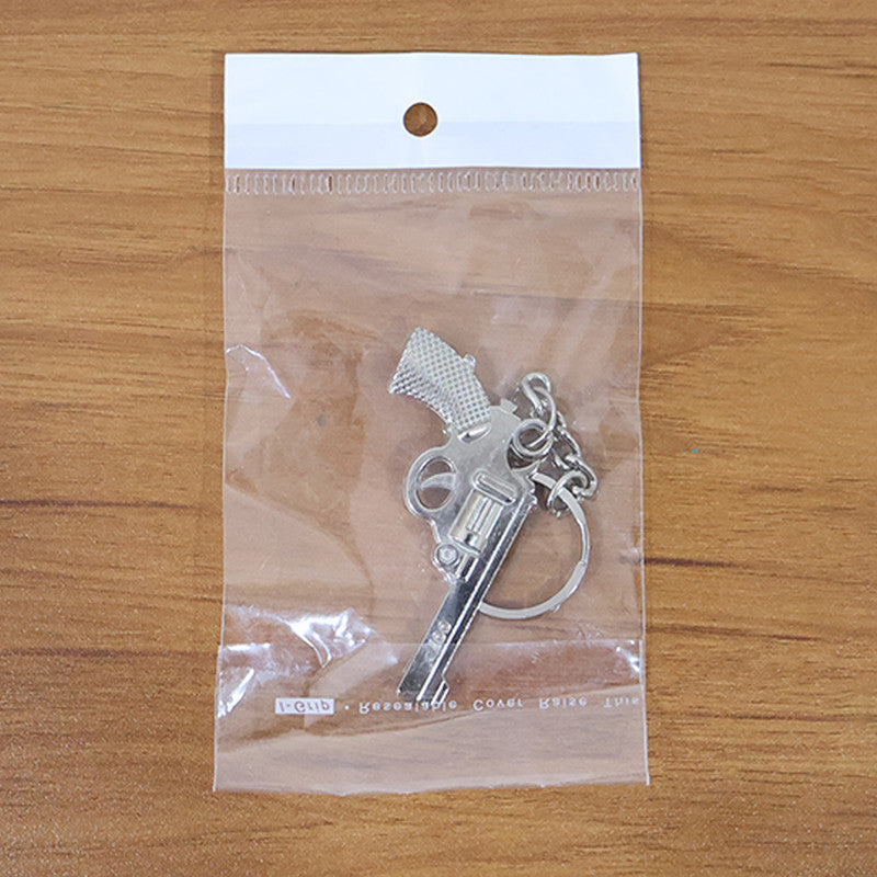 Trendy gun shape metal keychain stylishly hanging from a bag strap.