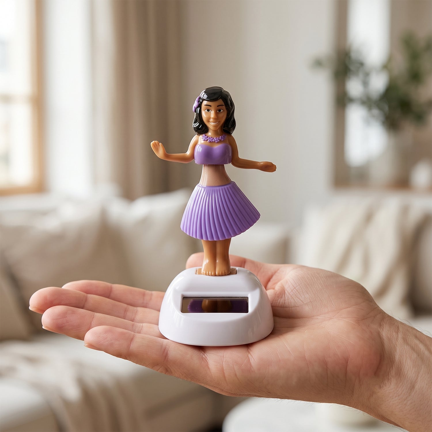 A solar-powered dancing hula girl toy in purple and brown, with a white base, held in a person's open palm indoors.