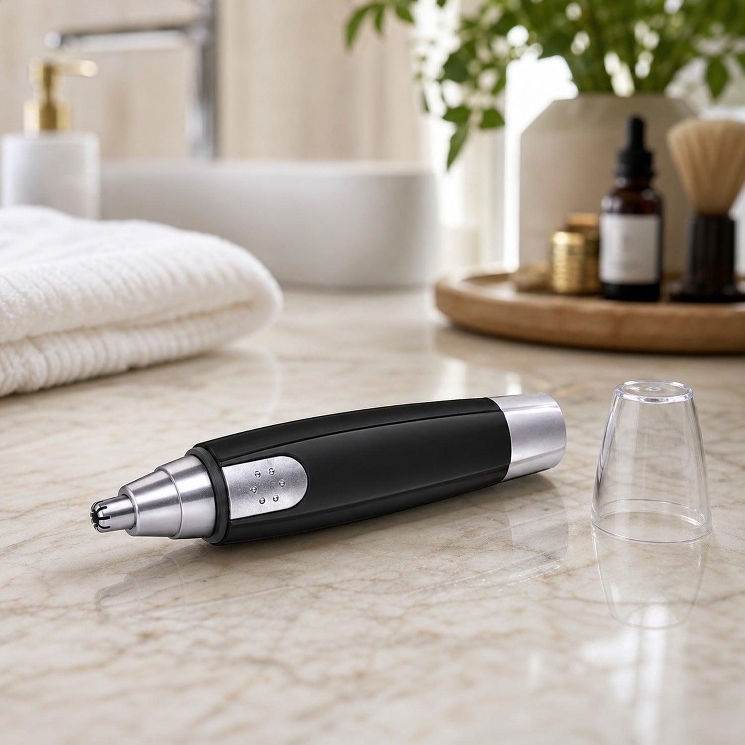 A black and silver nose hair trimmer lies on a marble counter with its clear cap next to it.