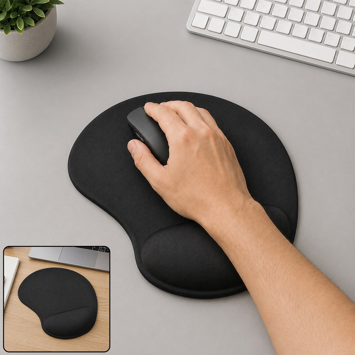 A hand using a mouse on a black ergonomic mouse pad with wrist support, next to a keyboard and plant.