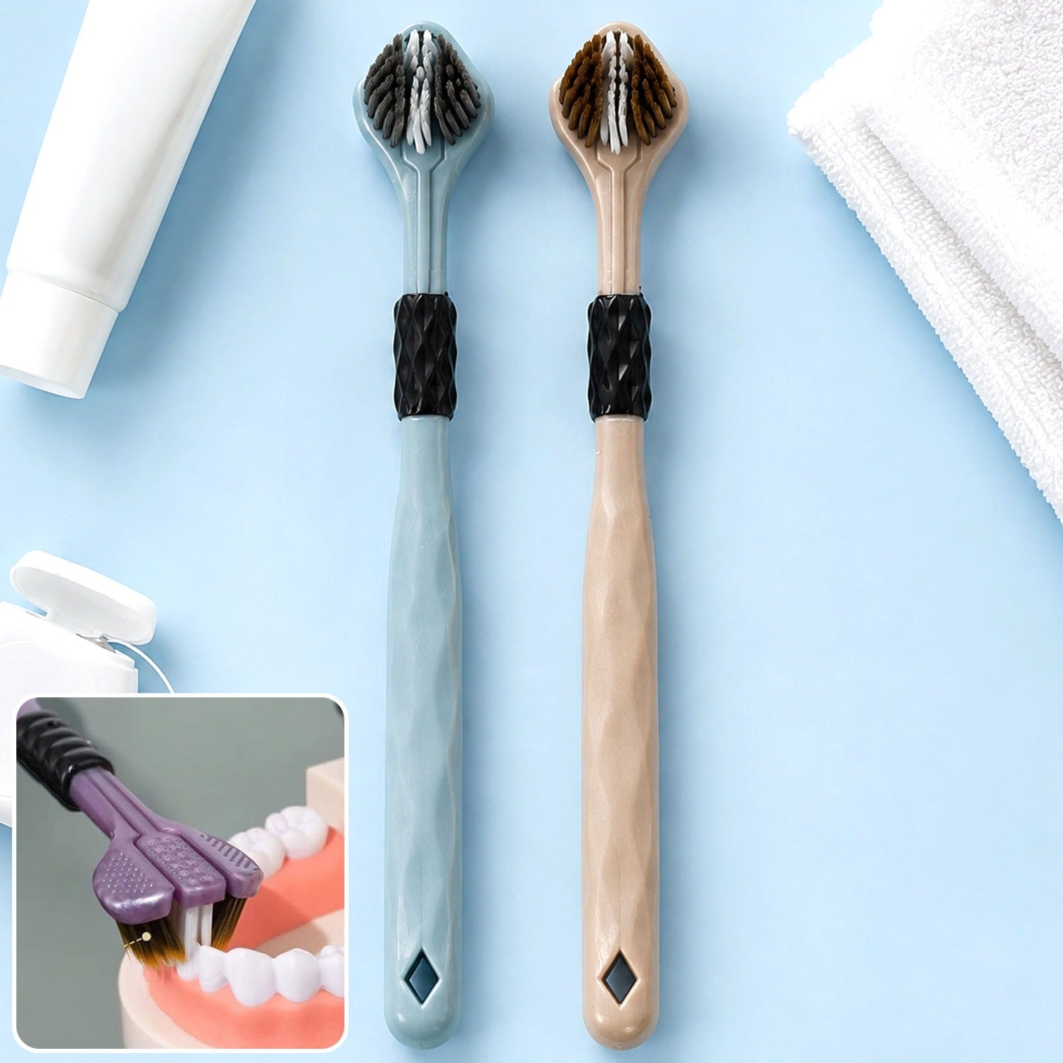 Two three-sided toothbrushes, one blue and one beige, with white toothpaste and dental floss in the background.