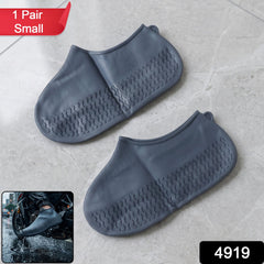 Two small grey silicone shoe covers with textured soles are displayed on a light grey tiled surface, with a small inset